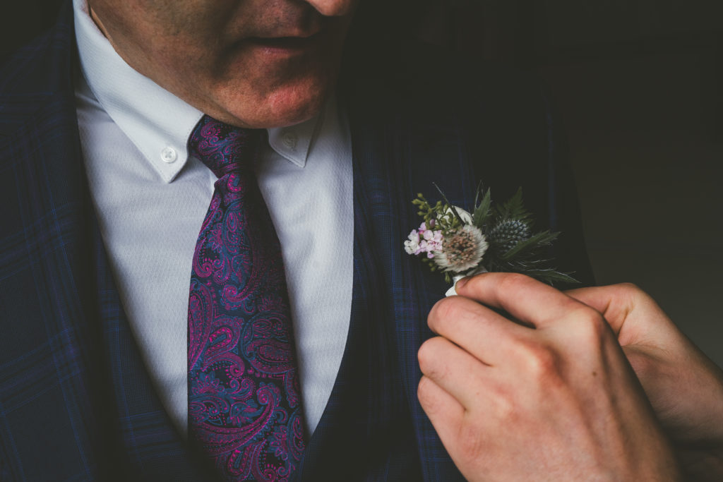 the best man pins on the grooms button hole