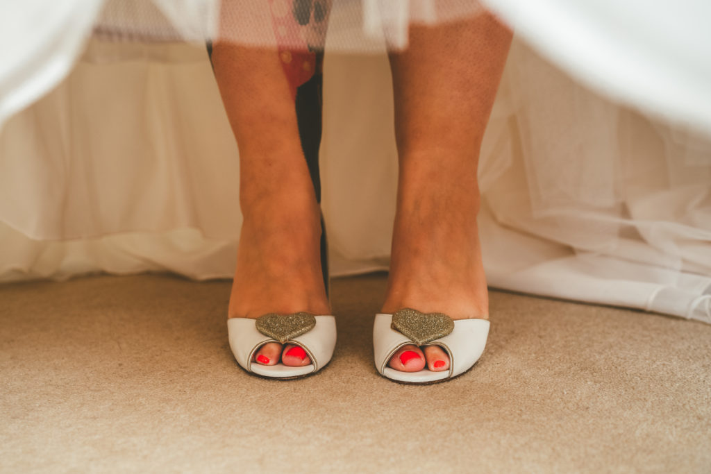 a bride to be shows off her wedding shoes beneath her wedding dress